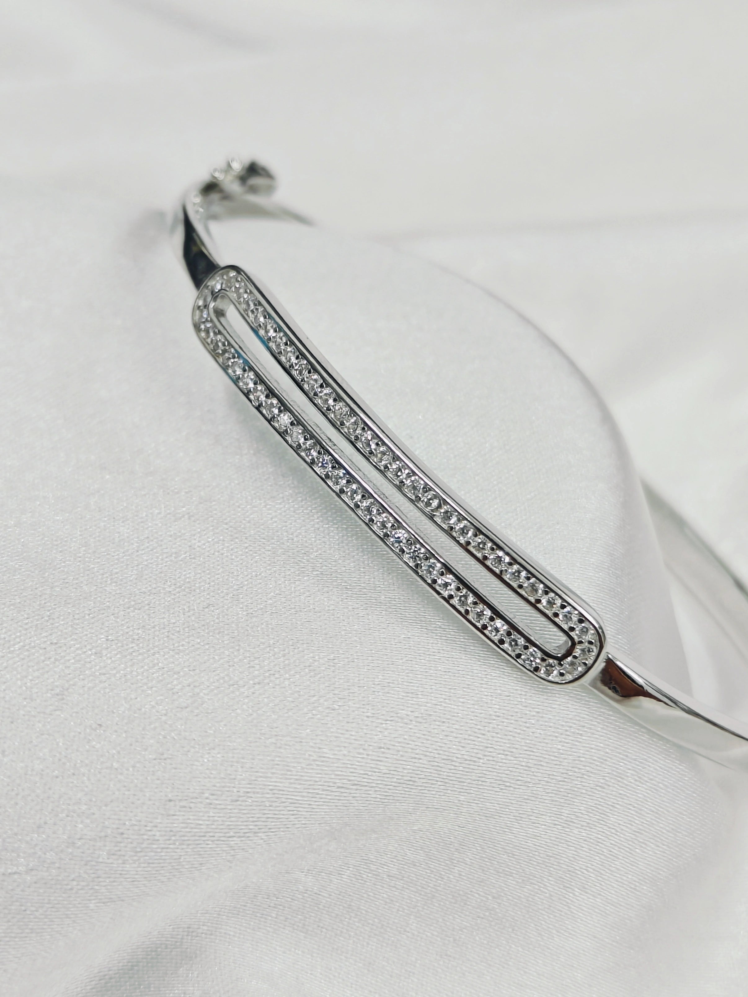 Silver bracelet with clear stones on a white fabric background
